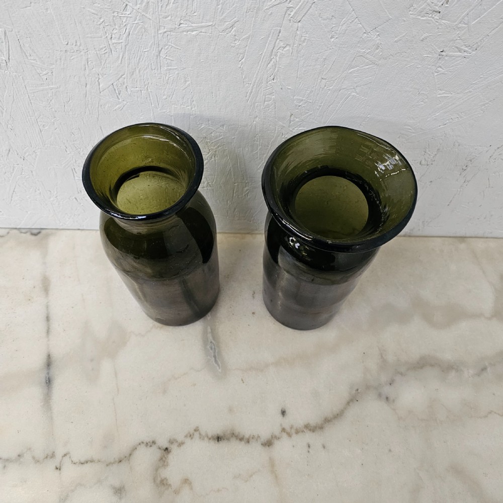 A pair of olive green hand-blown glass jars with cylindrical bases and wide flared rims. View III