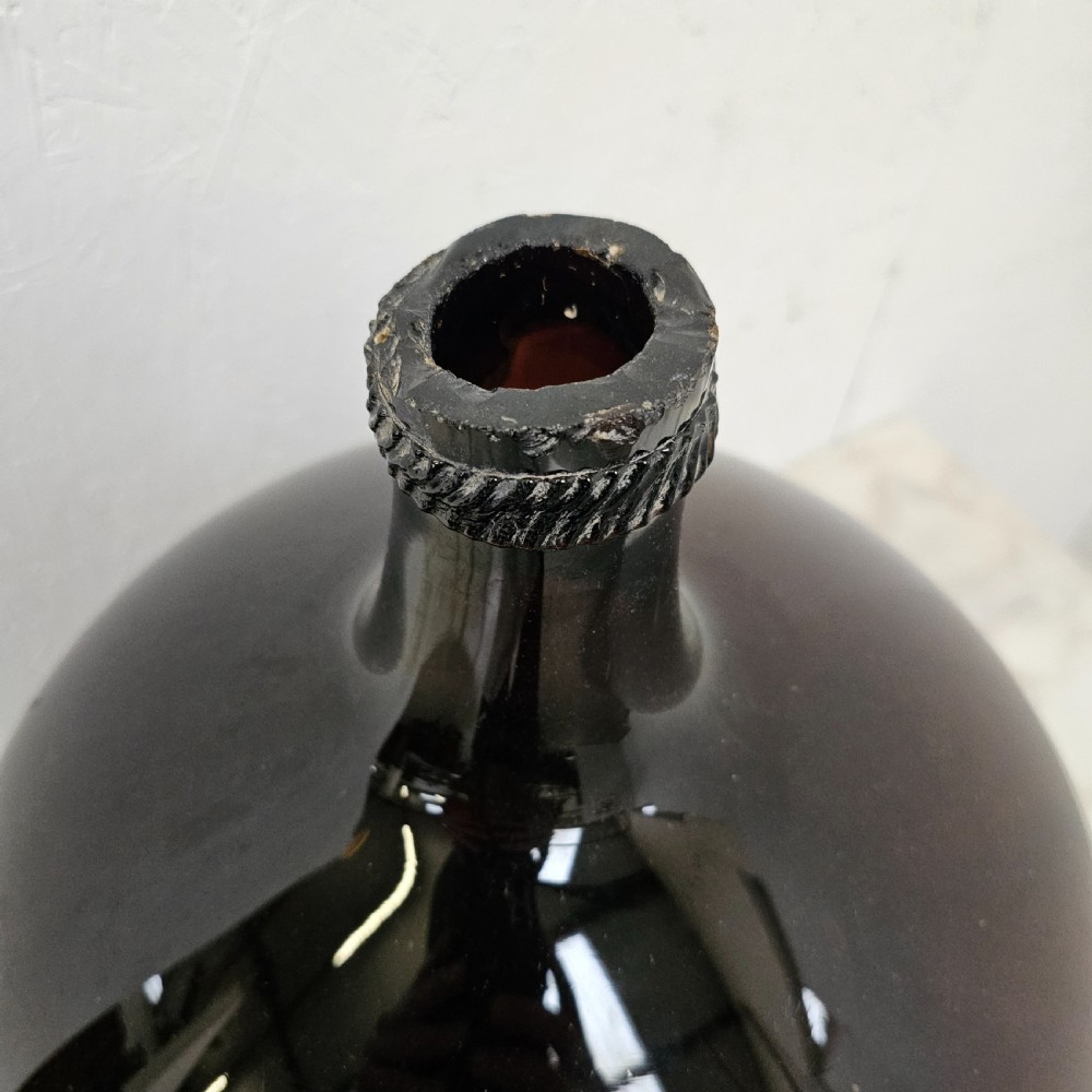 A large globular hand-blown glass jar in deep burgundy with a short tapered neck and an applied string rim. View II