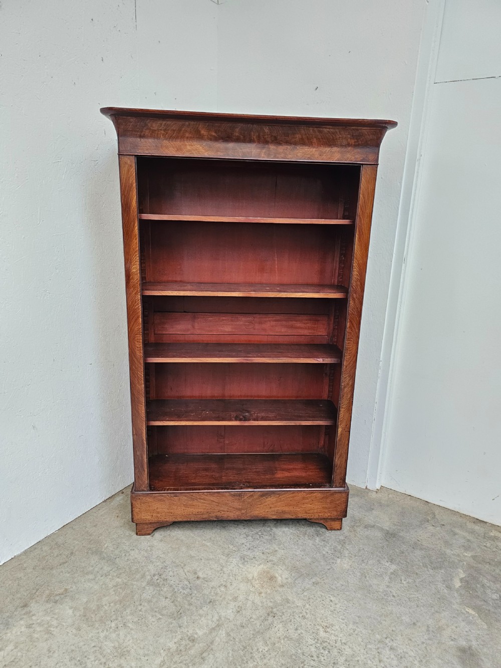 A 19th-century French open bookcase crafted from warm brown walnut wood featuring five adjustable shelves and a classic plinth base.