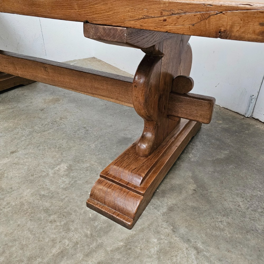 A long French pale oak trestle dining table featuring a solid plank top supported by shaped pedestal legs and a low central stretcher. View IV
