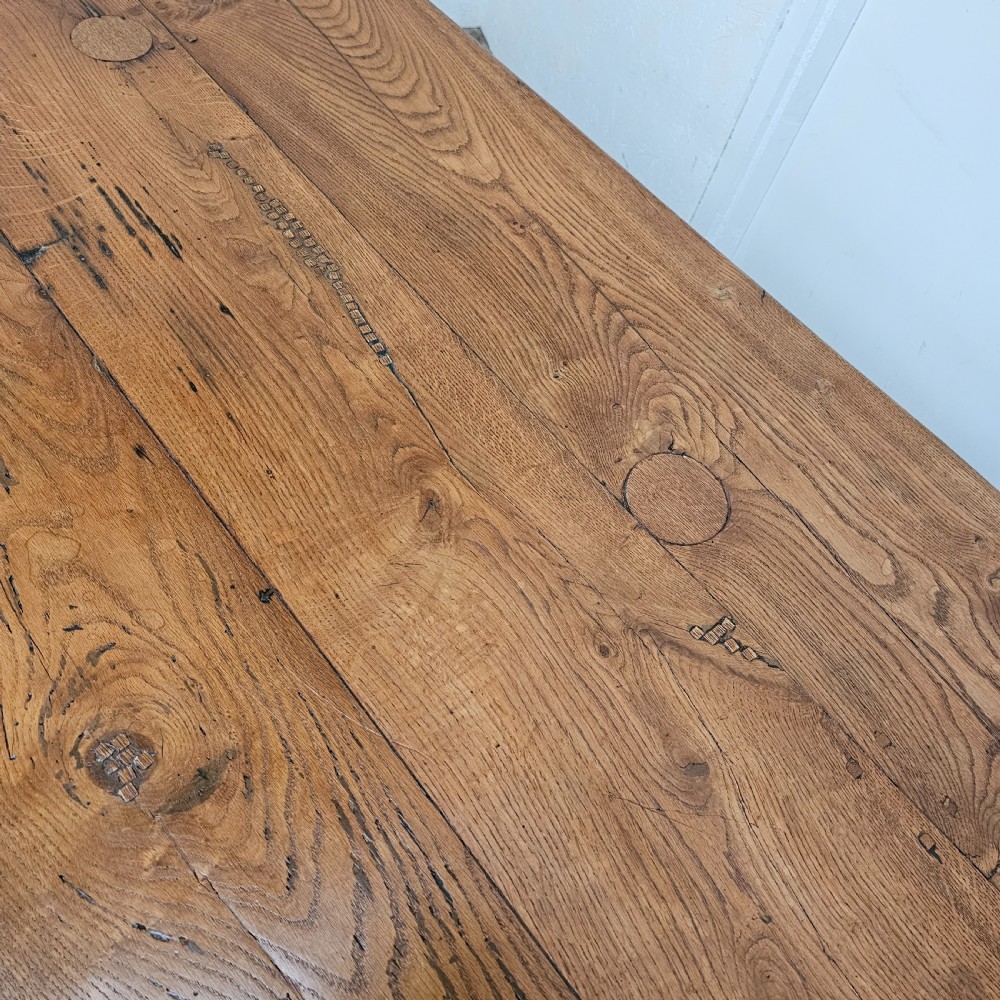 A long French pale oak trestle dining table featuring a solid plank top supported by shaped pedestal legs and a low central stretcher. View VI