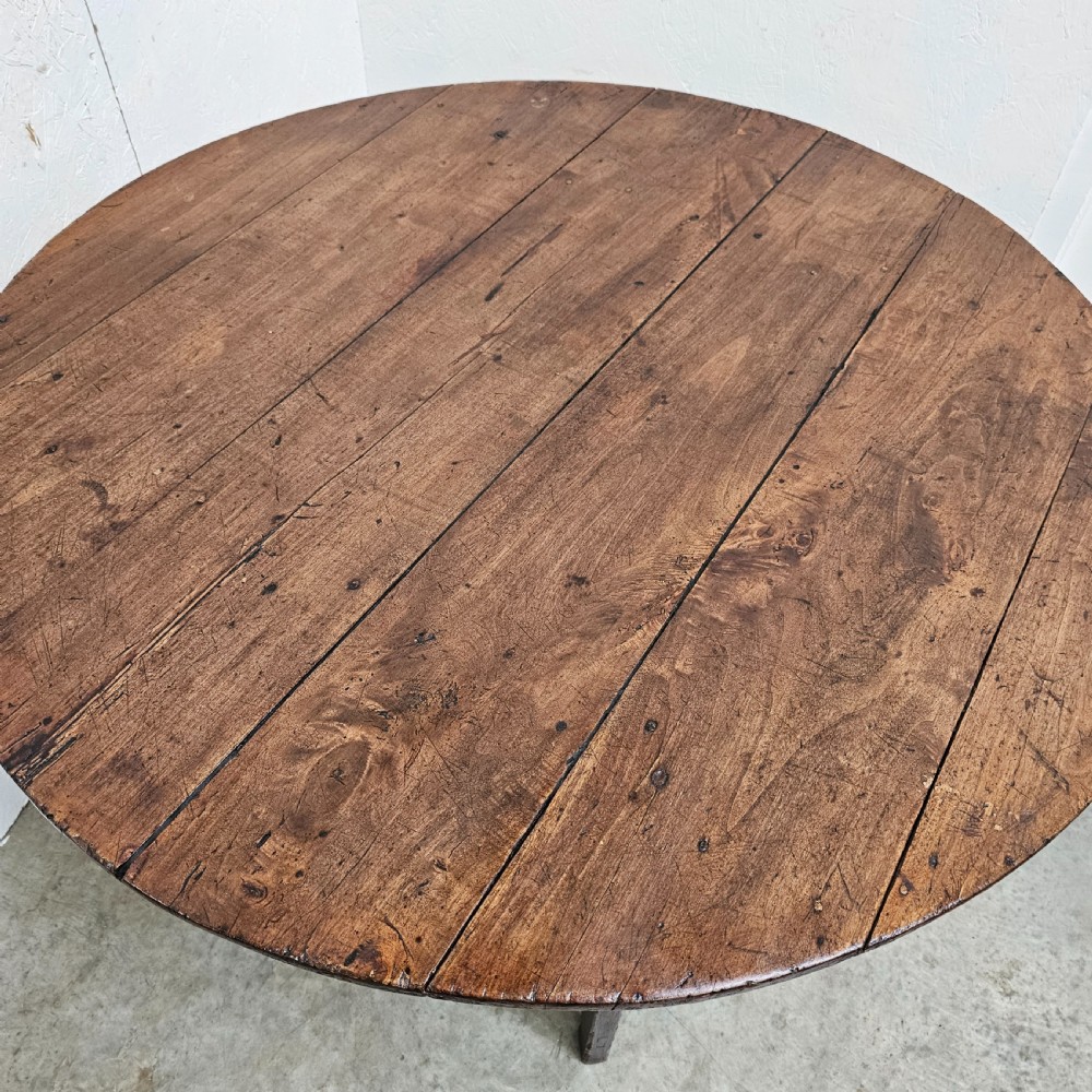 An antique dark oak French folding vineyard table with a circular planked tilt top and a wooden cross-trestle base. View V