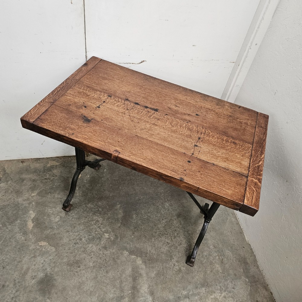 A rectangular oak wood tabletop mounted on a black cast iron frame with cross-braced legs. View II