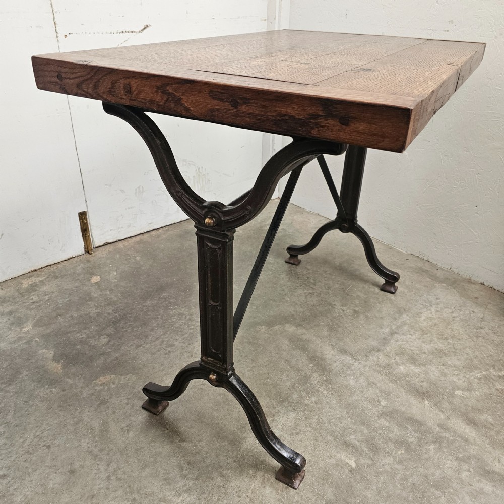 A rectangular oak wood tabletop mounted on a black cast iron frame with cross-braced legs. View III