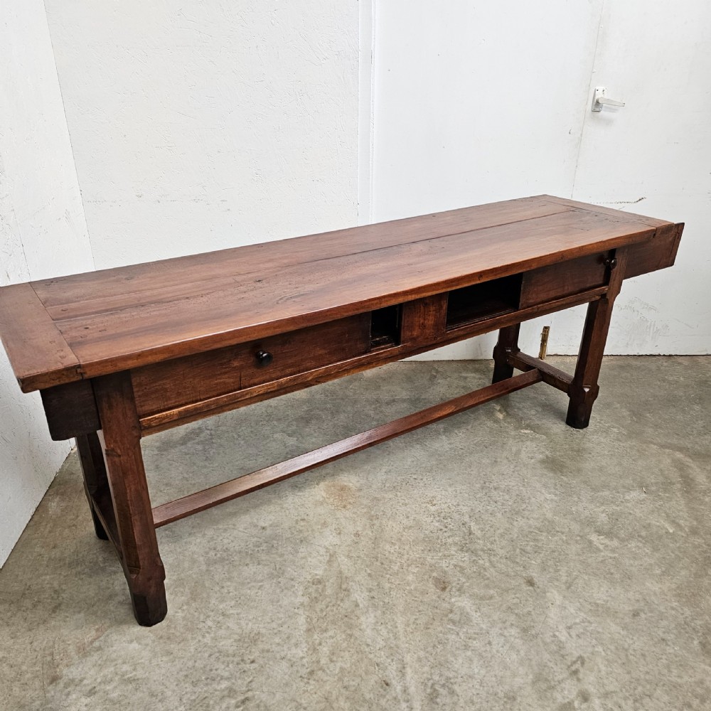 A long 19th-century dark brown wooden bread prep table featuring two drawers with round knobs and a low horizontal stretcher. View V