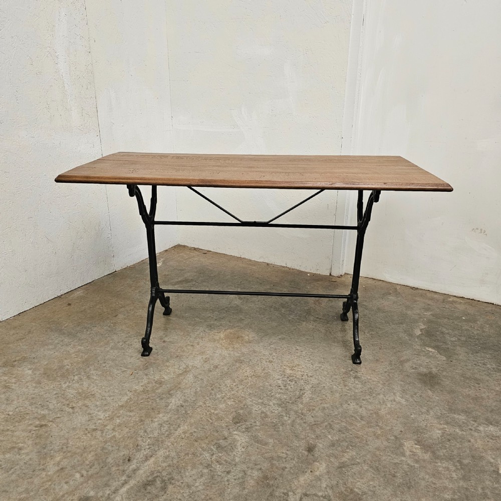 A rectangular natural oak tabletop supported by a black painted iron frame with diagonal cross bracing.