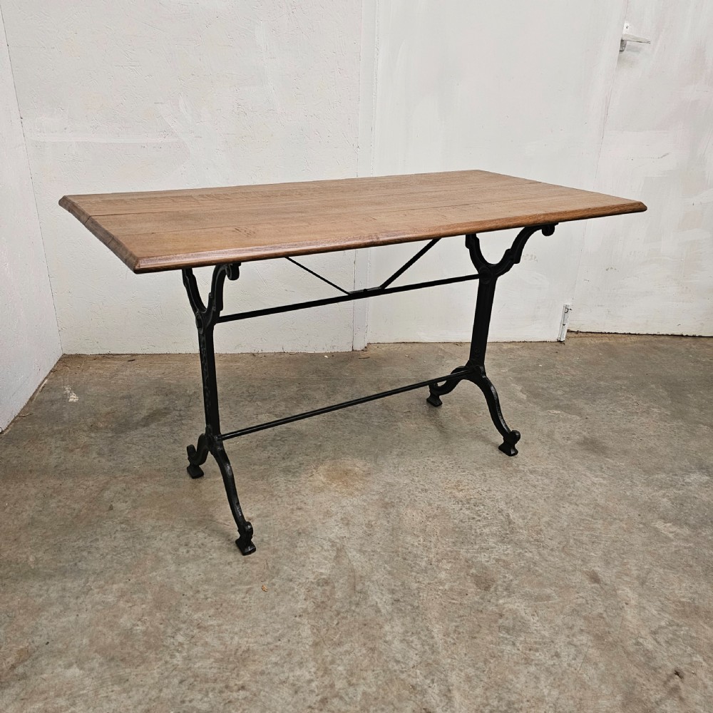 A rectangular natural oak tabletop supported by a black painted iron frame with diagonal cross bracing. View II