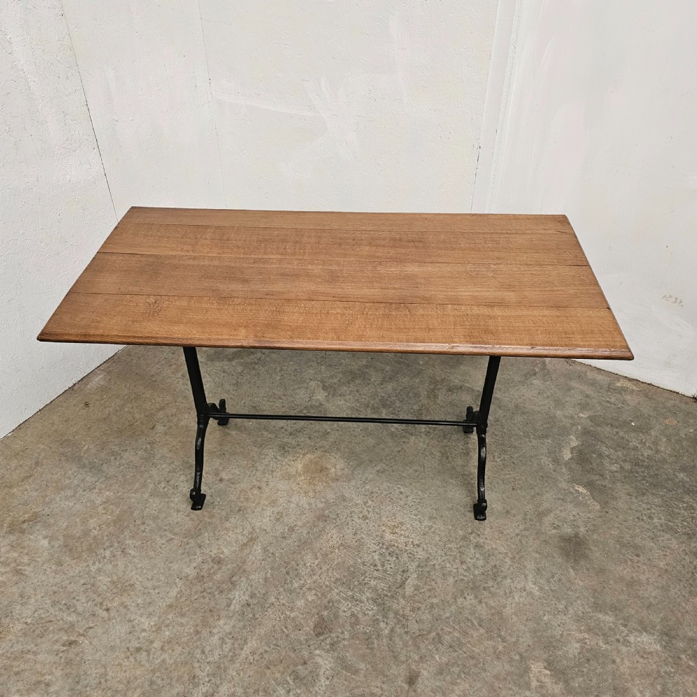 A rectangular natural oak tabletop supported by a black painted iron frame with diagonal cross bracing. View III