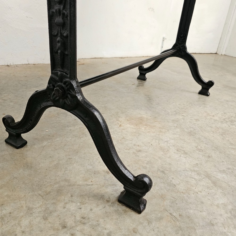 A rectangular natural oak tabletop supported by a black painted iron frame with diagonal cross bracing. View V