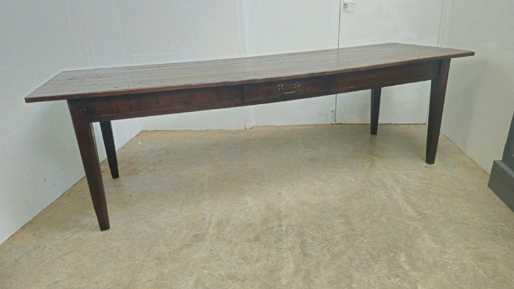 An eight-foot antique French dark oak farmhouse table featuring a plank top, frieze drawer with iron drop handle, and tapered square legs. View VI