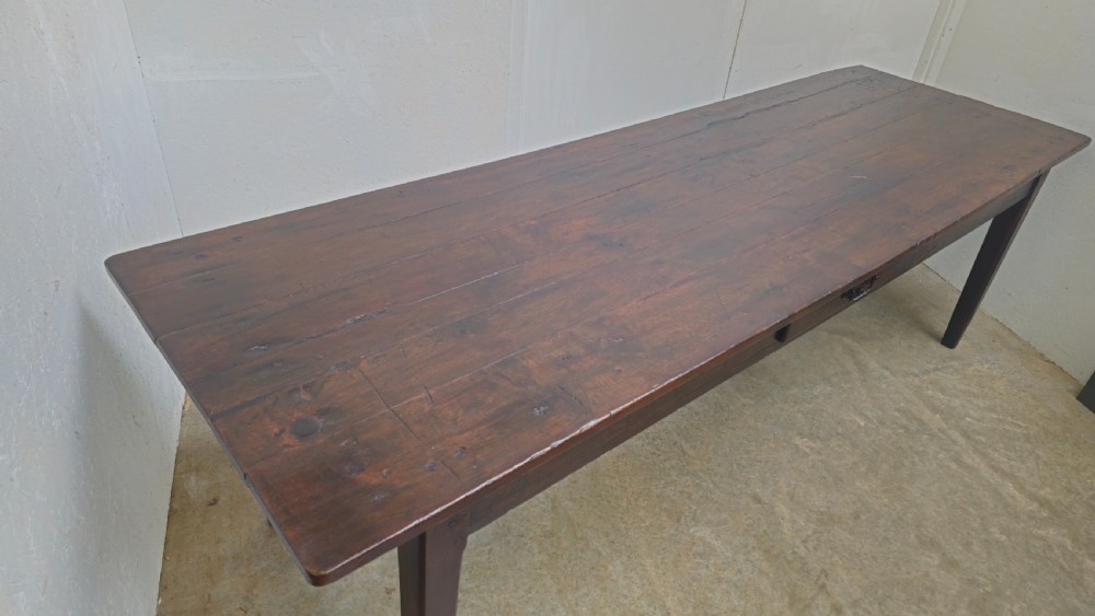 An eight-foot antique French dark oak farmhouse table featuring a plank top, frieze drawer with iron drop handle, and tapered square legs. View II