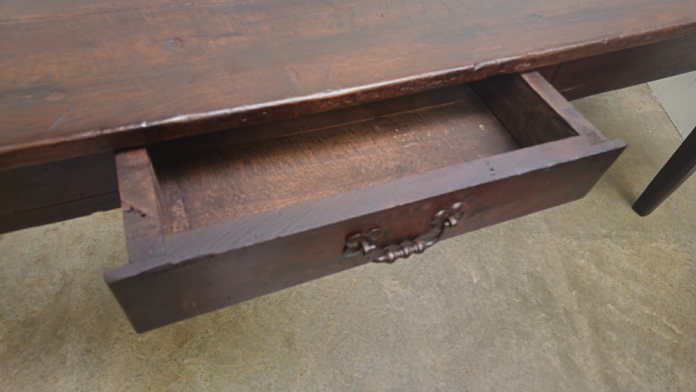 An eight-foot antique French dark oak farmhouse table featuring a plank top, frieze drawer with iron drop handle, and tapered square legs. View III