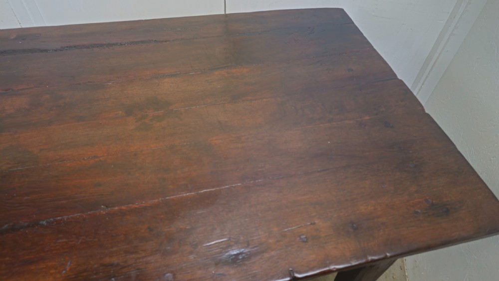 An eight-foot antique French dark oak farmhouse table featuring a plank top, frieze drawer with iron drop handle, and tapered square legs. View IV