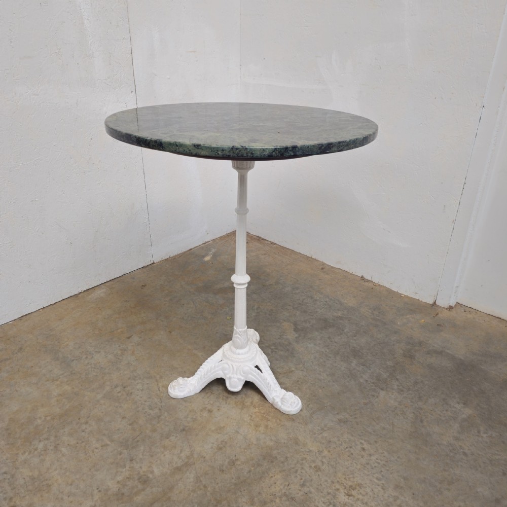 A circular green marble bistro table featuring a white painted cast iron pedestal stem with three decorative feet.