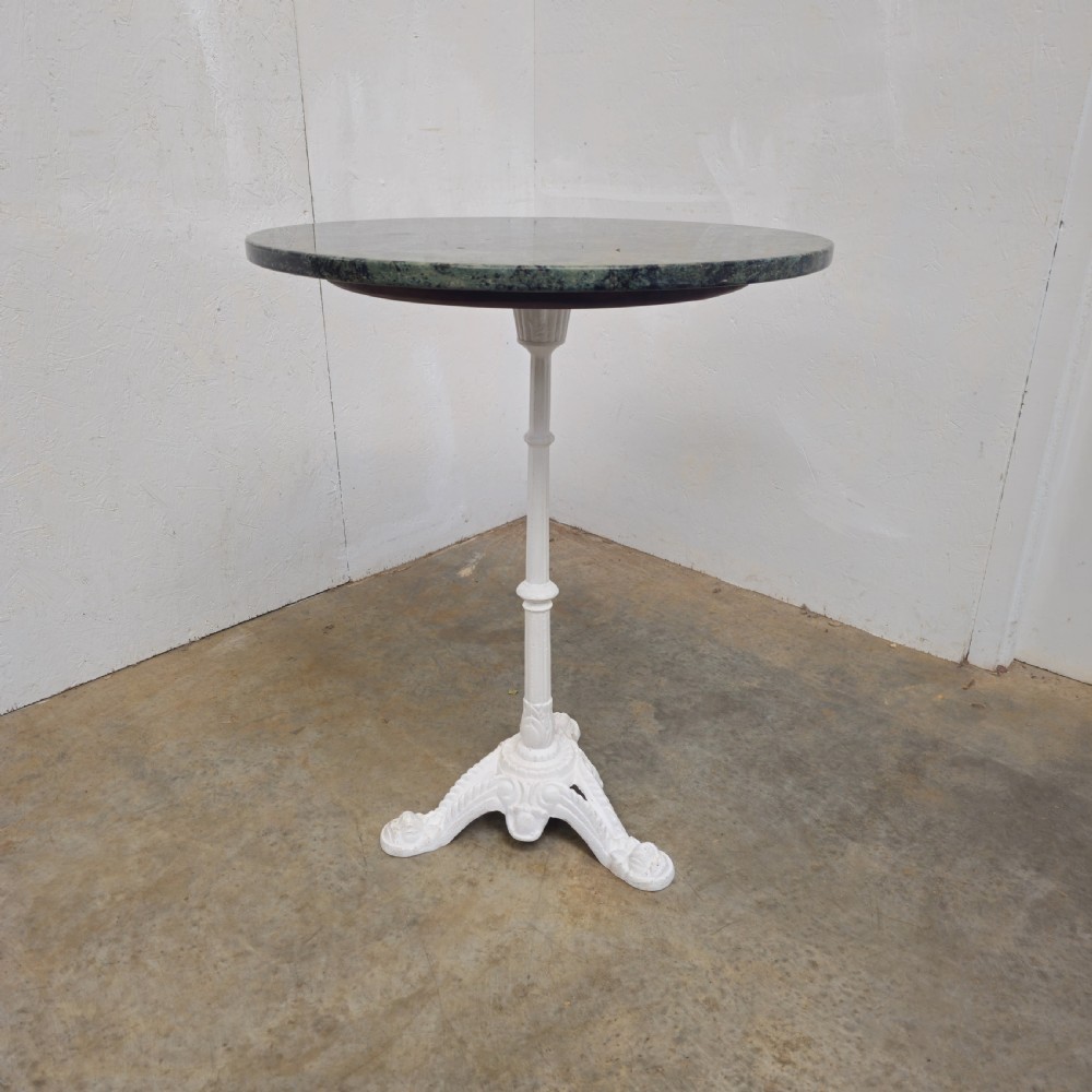 A circular green marble bistro table featuring a white painted cast iron pedestal stem with three decorative feet. View II