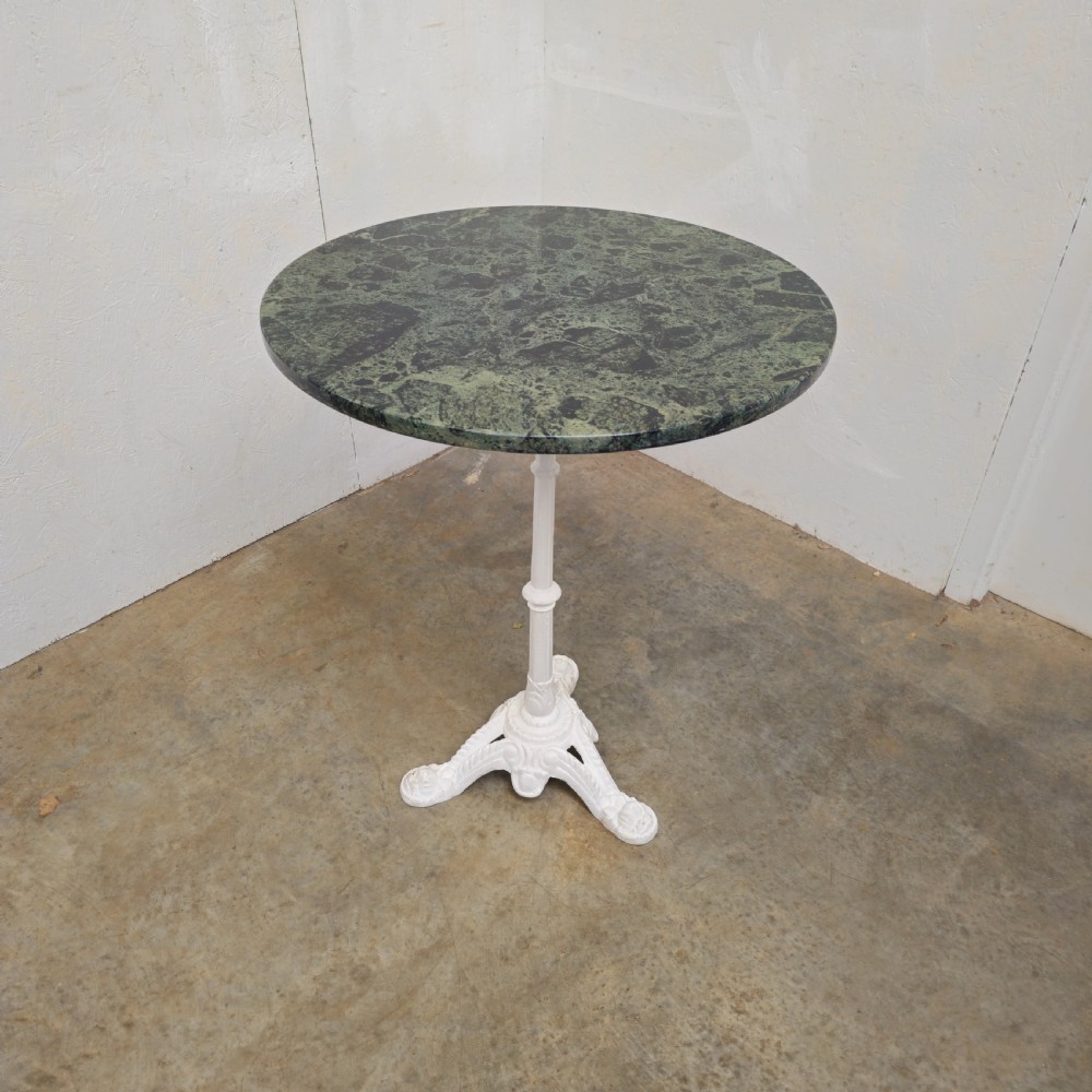 A circular green marble bistro table featuring a white painted cast iron pedestal stem with three decorative feet. View III