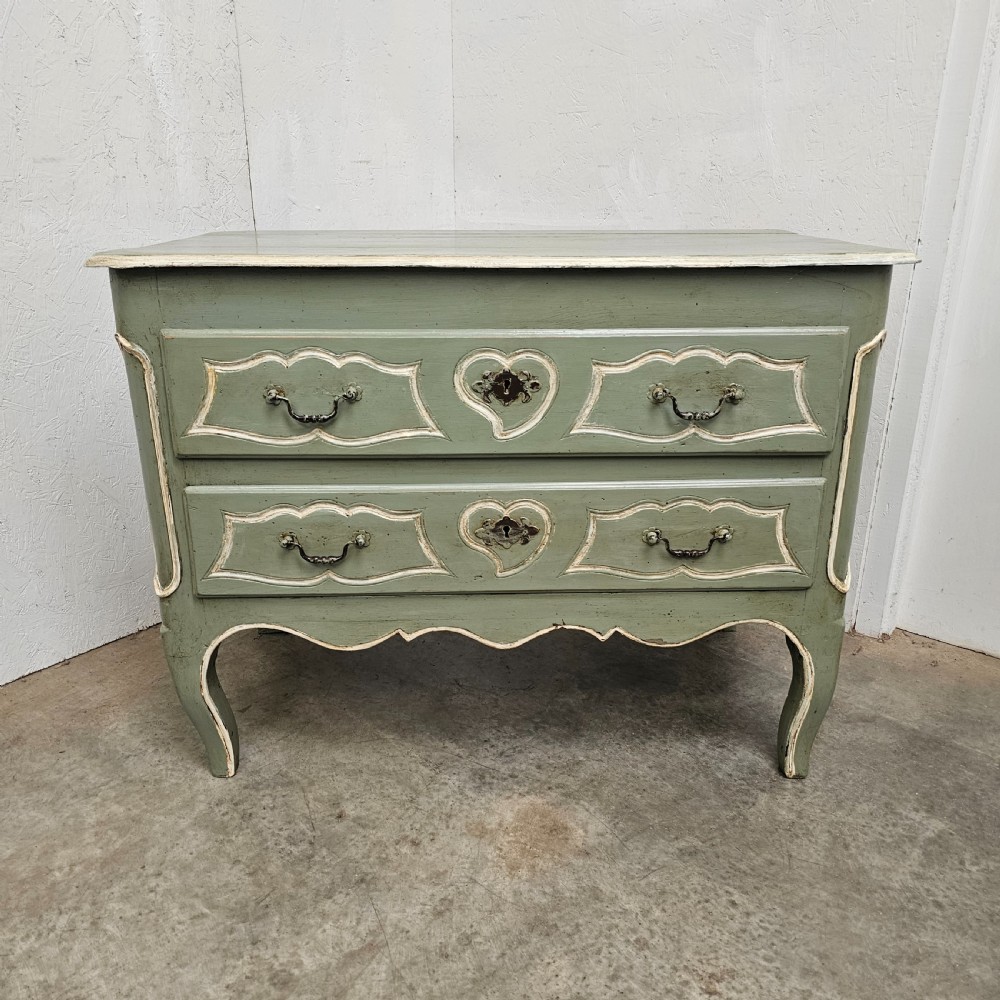 An 18th-century French provincial painted commode featuring two long drawers finished in muted green paint with cream trim and metal handles.