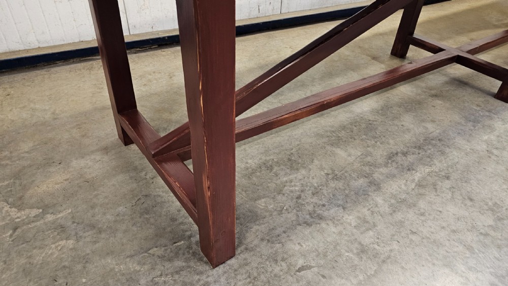 An exceptionally long antique pine harvest table featuring a plank wood top supported by a dark stained frame with cross-bracing. View VIII