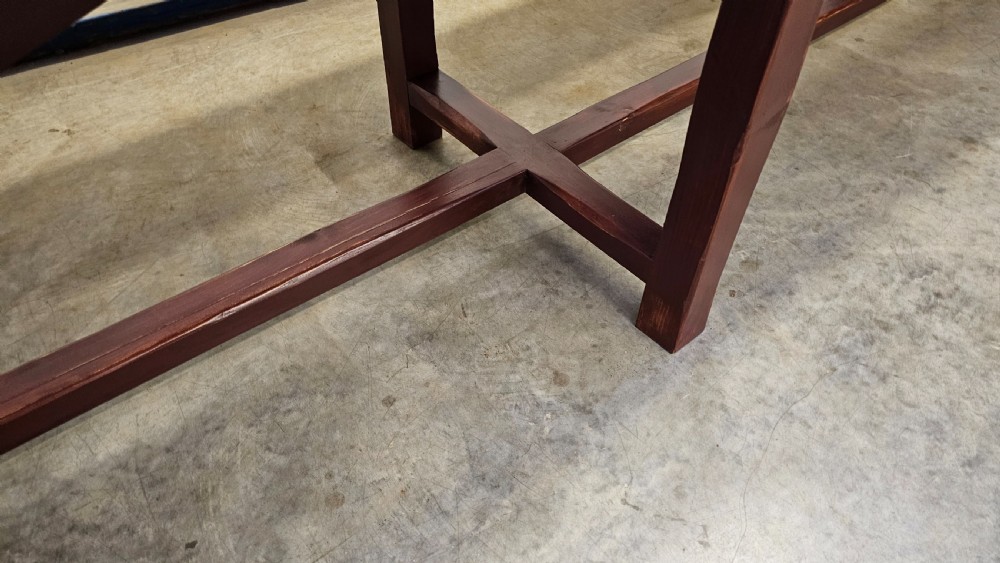 An exceptionally long antique pine harvest table featuring a plank wood top supported by a dark stained frame with cross-bracing. View IX
