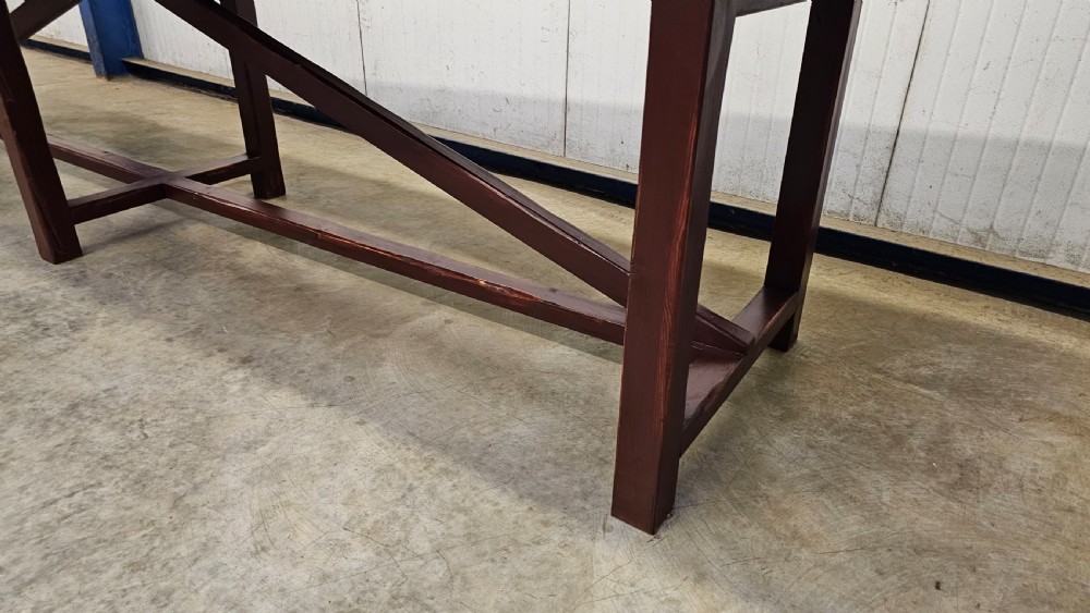 An exceptionally long antique pine harvest table featuring a plank wood top supported by a dark stained frame with cross-bracing. View X