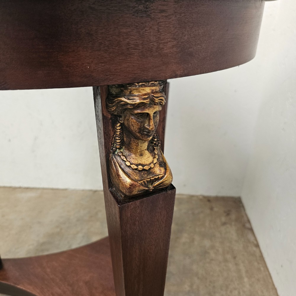 A circular 19th-century French Empire style gueridon featuring a dark marble top supported by tapered mahogany legs adorned with gilt female busts and a triform base. View III