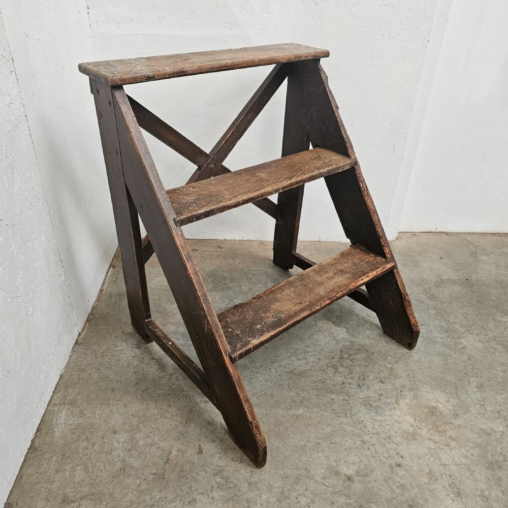 A three-tier dark pine wooden step stool featuring an A-frame structure with a cross-brace on the reverse. View IV