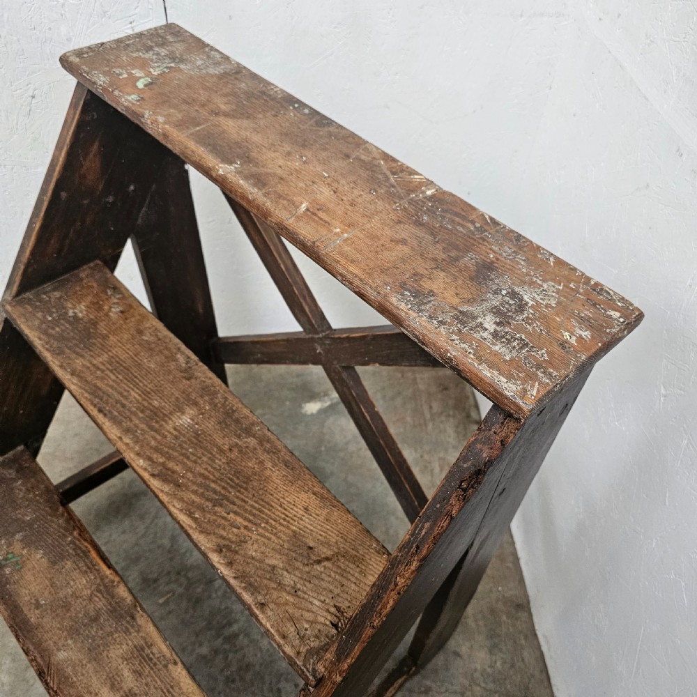 A three-tier dark pine wooden step stool featuring an A-frame structure with a cross-brace on the reverse. View VI
