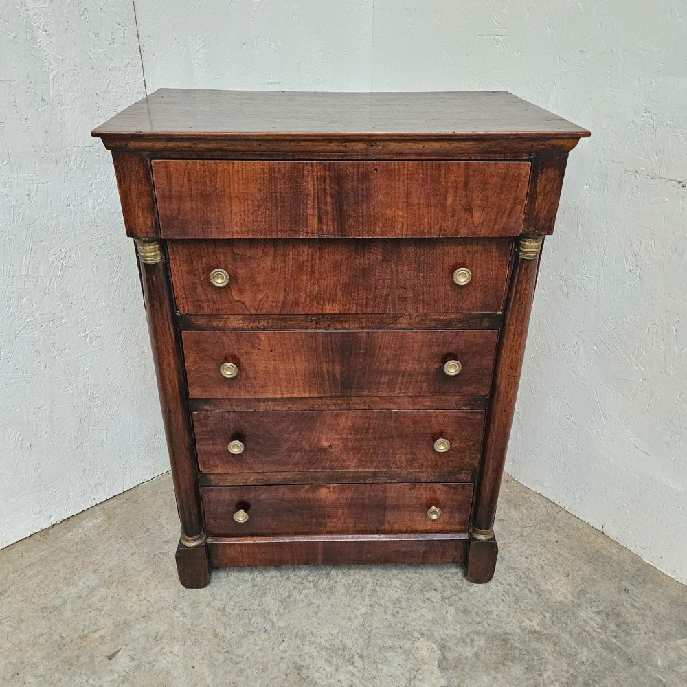A five-drawer French Empire style mahogany chest featuring brass knobs and flanking pilaster columns.