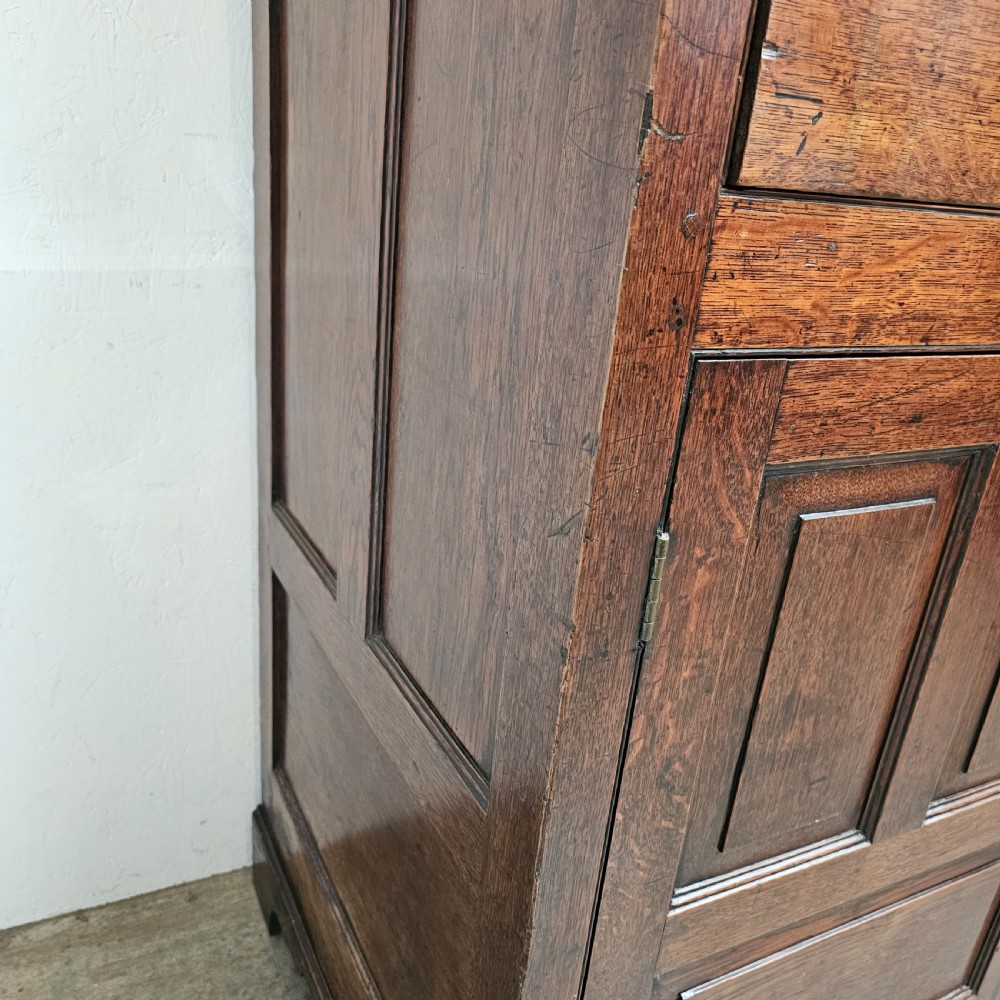An eighteenth-century dark oak Welsh deuddarn press cupboard featuring three ogee arched upper doors above drawers and fielded lower panel doors. View II