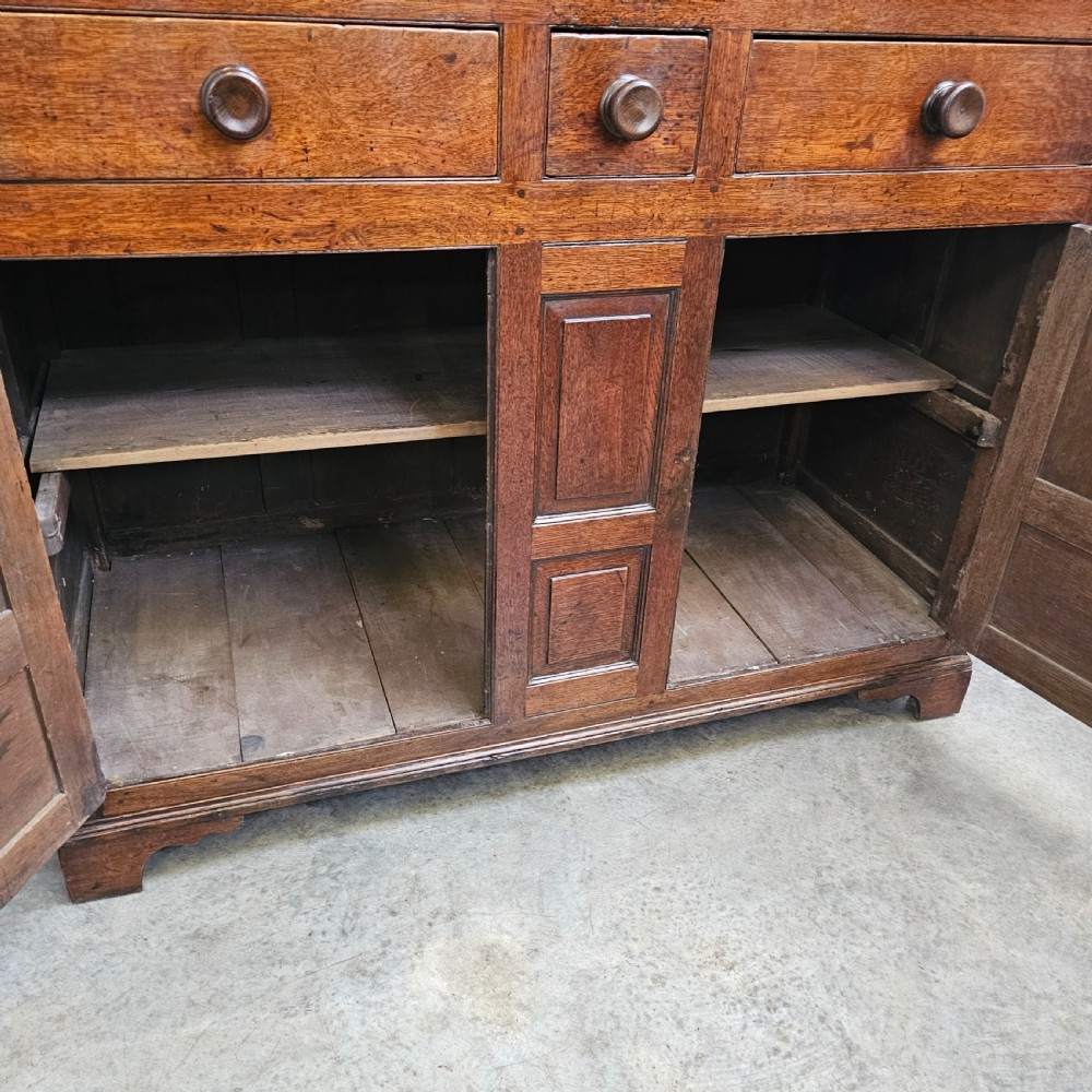 An eighteenth-century dark oak Welsh deuddarn press cupboard featuring three ogee arched upper doors above drawers and fielded lower panel doors. View III