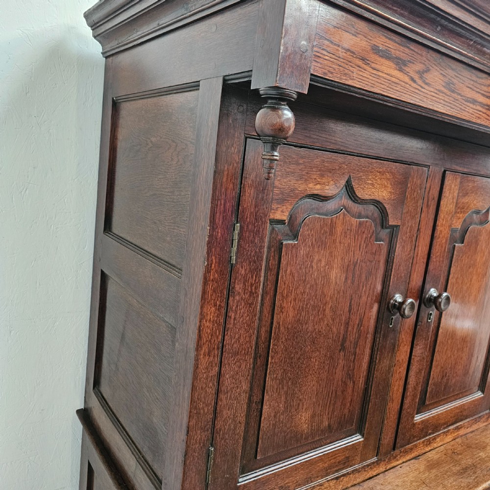 An eighteenth-century dark oak Welsh deuddarn press cupboard featuring three ogee arched upper doors above drawers and fielded lower panel doors. View V