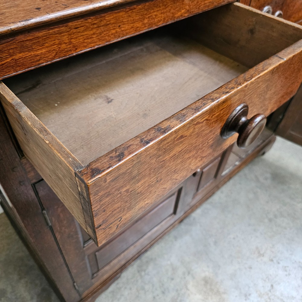 An eighteenth-century dark oak Welsh deuddarn press cupboard featuring three ogee arched upper doors above drawers and fielded lower panel doors. View IX