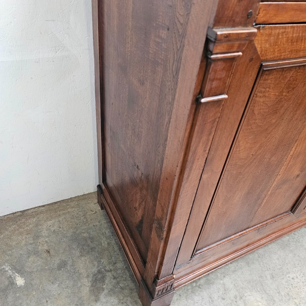 A tall cherrywood Directoire buffet featuring three drawers above two large panelled cupboard doors with brass knobs and fluted pilasters. View III
