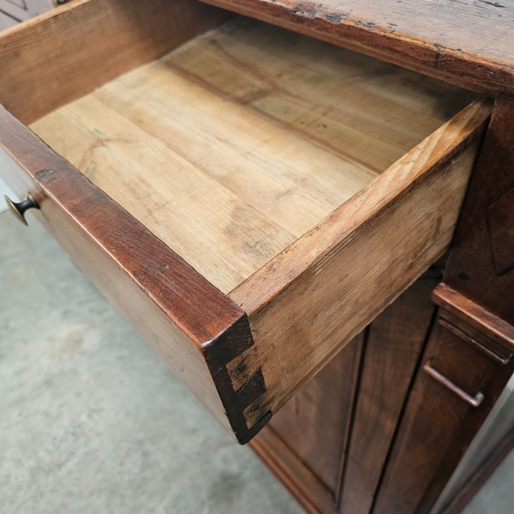 A tall cherrywood Directoire buffet featuring three drawers above two large panelled cupboard doors with brass knobs and fluted pilasters. View VI