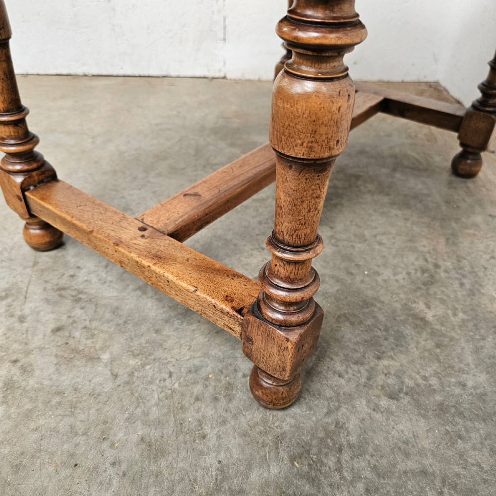 A small antique French walnut end table featuring turned wooden legs, a low stretcher base, and a single drawer with a dark turned knob. View VI