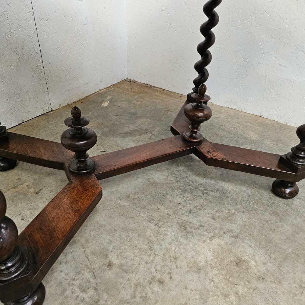 An antique dark walnut table featuring four barley twist legs, a stretcher base with decorative finials, and a single drawer with a central round wooden knob. View III