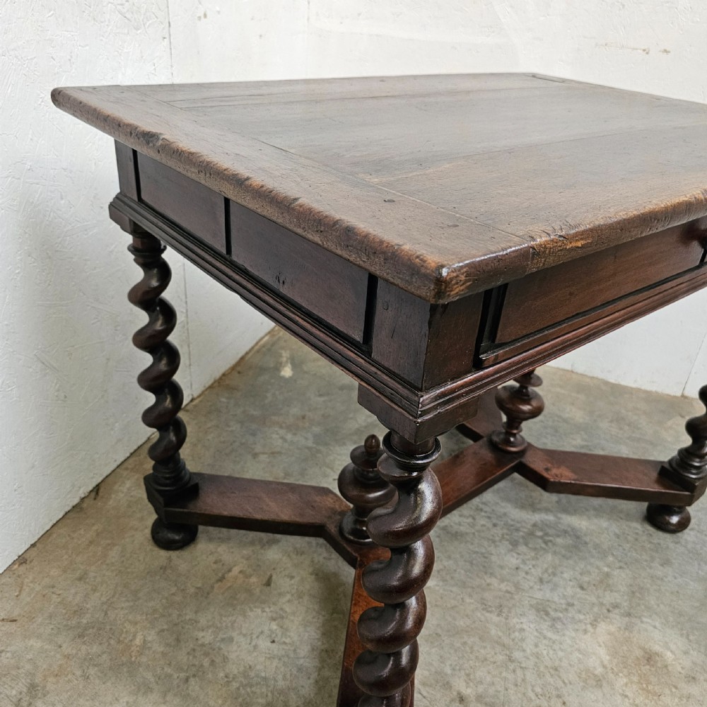 An antique dark walnut table featuring four barley twist legs, a stretcher base with decorative finials, and a single drawer with a central round wooden knob. View IV