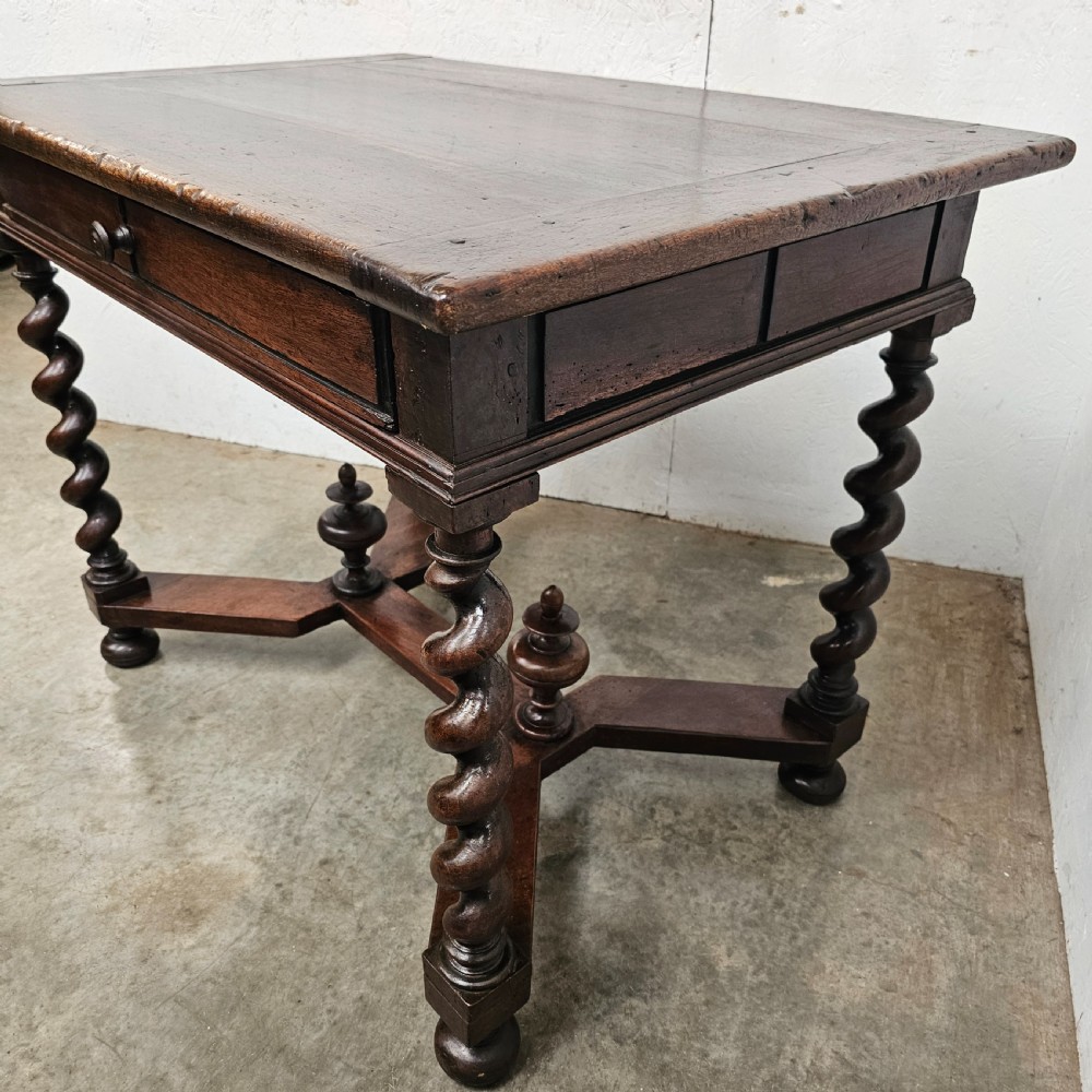 An antique dark walnut table featuring four barley twist legs, a stretcher base with decorative finials, and a single drawer with a central round wooden knob. View V