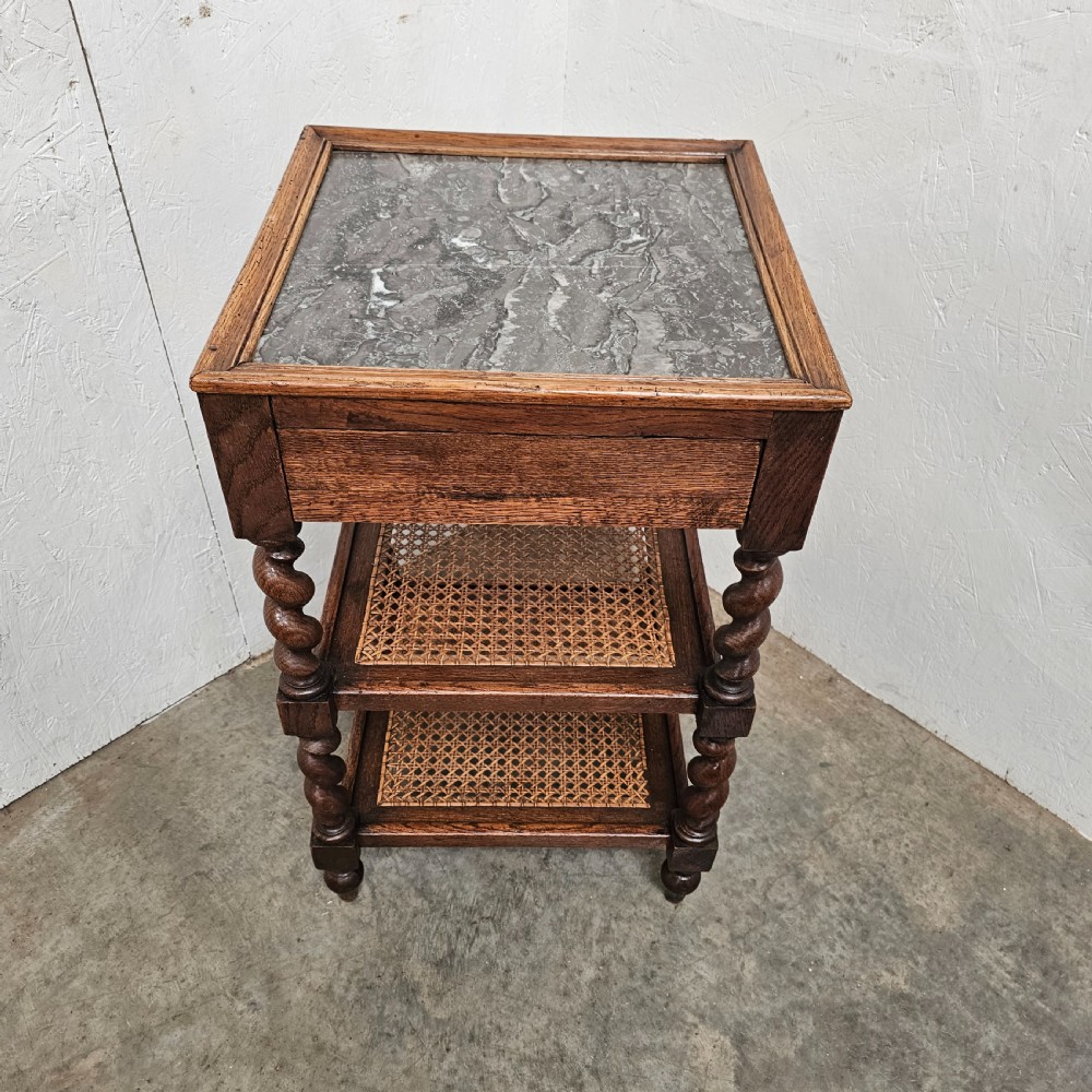 A French oak tiered etagere featuring an inset marble top, two woven cane lower shelves, and turned barley-twist supports. View II
