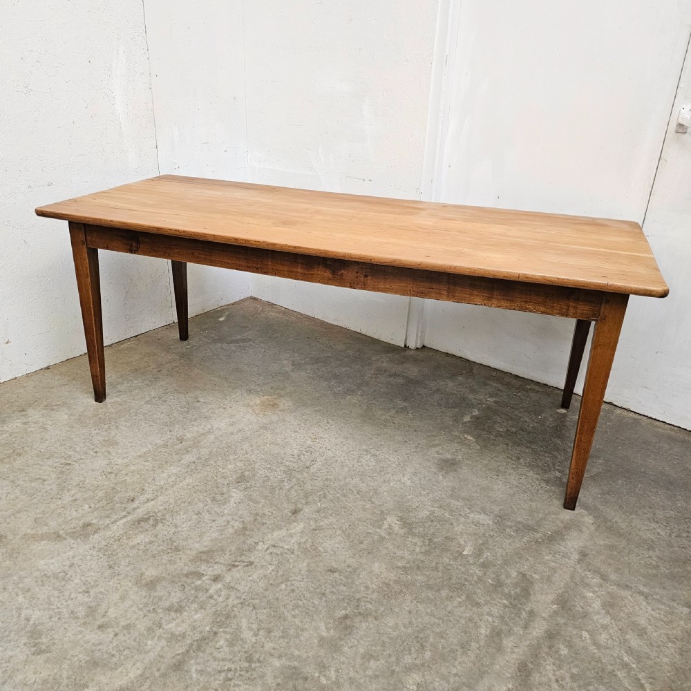 A nineteenth-century French farmhouse table made of faded cherrywood, featuring a rectangular plank top and four square tapered legs.
