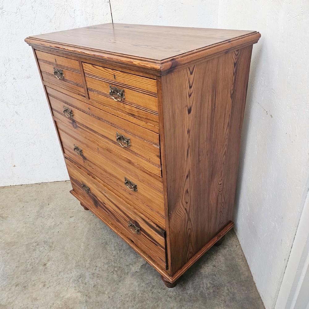 A Victorian pitch pine chest of drawers featuring two short over three long drawers with reeded details, brass handles, and turned bun feet. View III