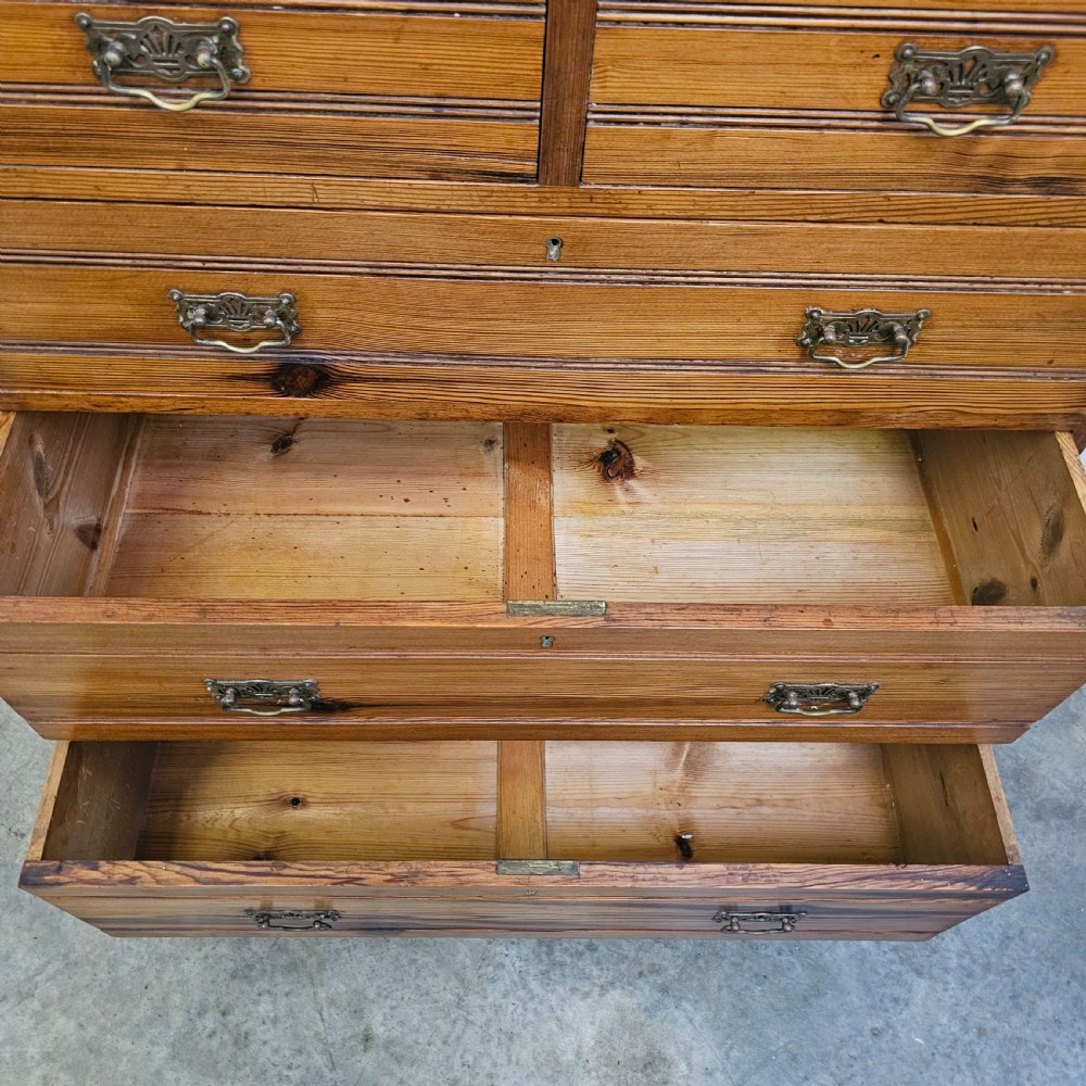 A Victorian pitch pine chest of drawers featuring two short over three long drawers with reeded details, brass handles, and turned bun feet. View VIII