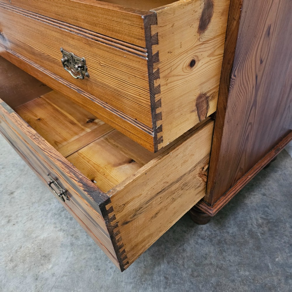 A Victorian pitch pine chest of drawers featuring two short over three long drawers with reeded details, brass handles, and turned bun feet. View IX