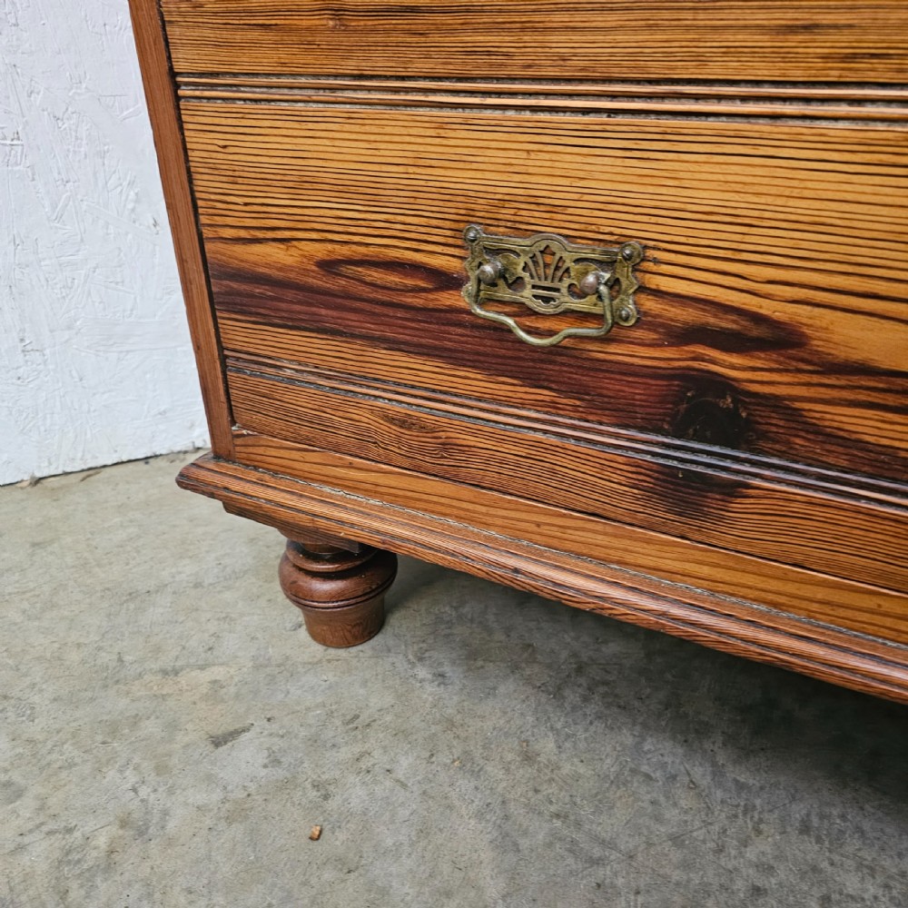 A Victorian pitch pine chest of drawers featuring two short over three long drawers with reeded details, brass handles, and turned bun feet. View XI