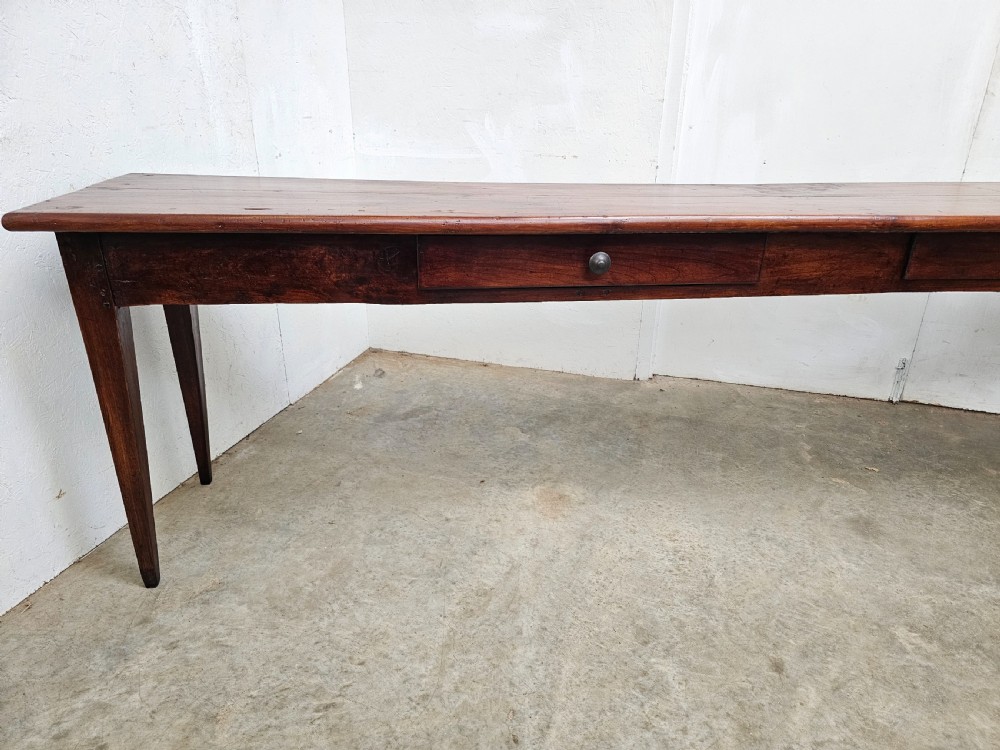 An exceptionally long French rustic wooden console table featuring two frieze drawers and simple tapered legs. View V