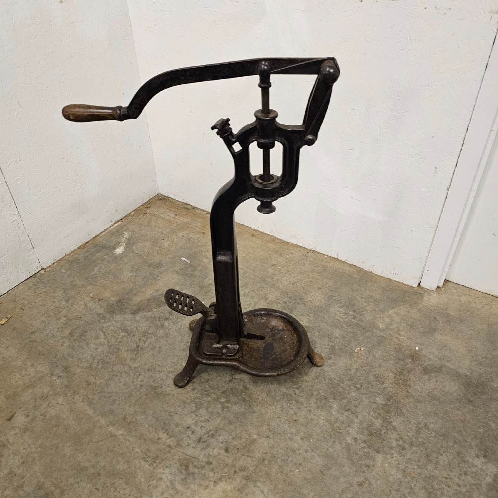 A floor-standing black cast iron antique French wine bottle corker with a long hand lever, wooden grip, plunger mechanism, and tripod base. View II