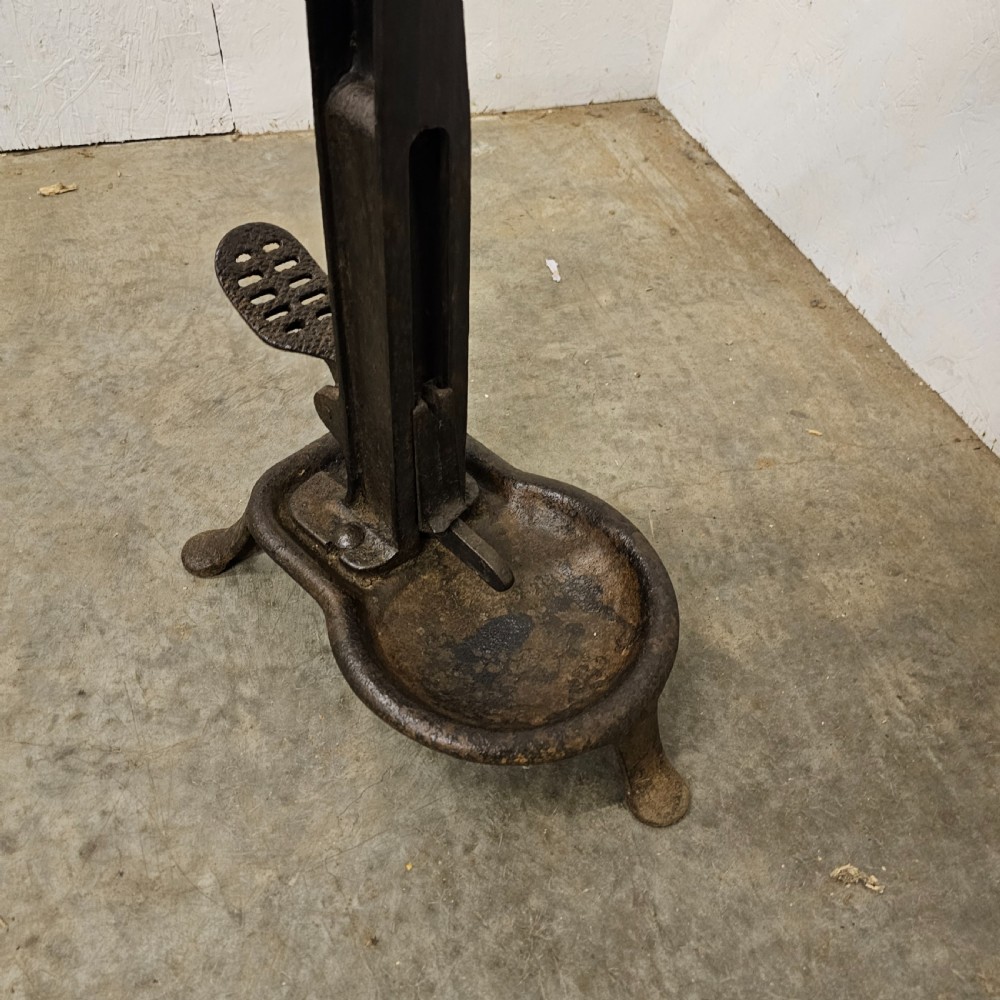 A floor-standing black cast iron antique French wine bottle corker with a long hand lever, wooden grip, plunger mechanism, and tripod base. View III