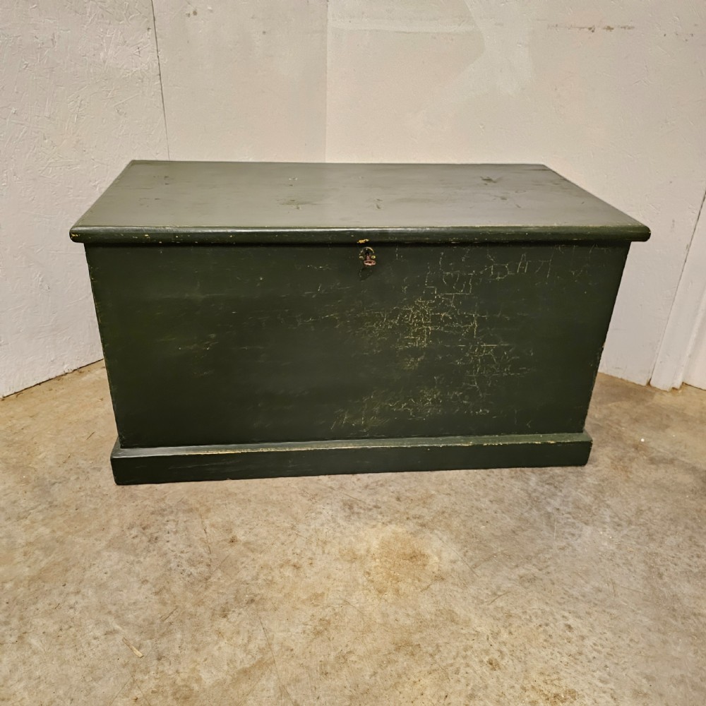 A rectangular green painted pine blanket box with side iron handles, a key in the lock, and a solid plinth base. View II