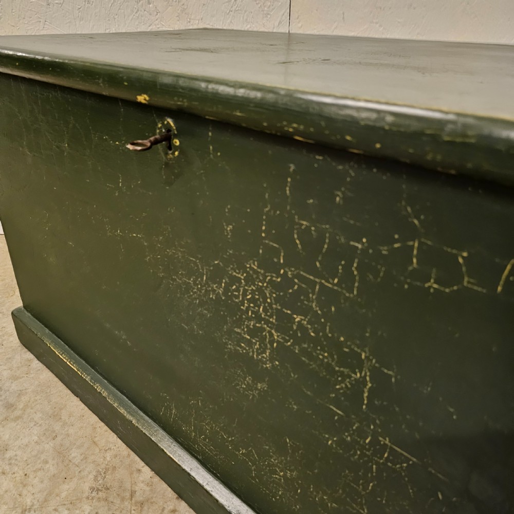 A rectangular green painted pine blanket box with side iron handles, a key in the lock, and a solid plinth base. View VI