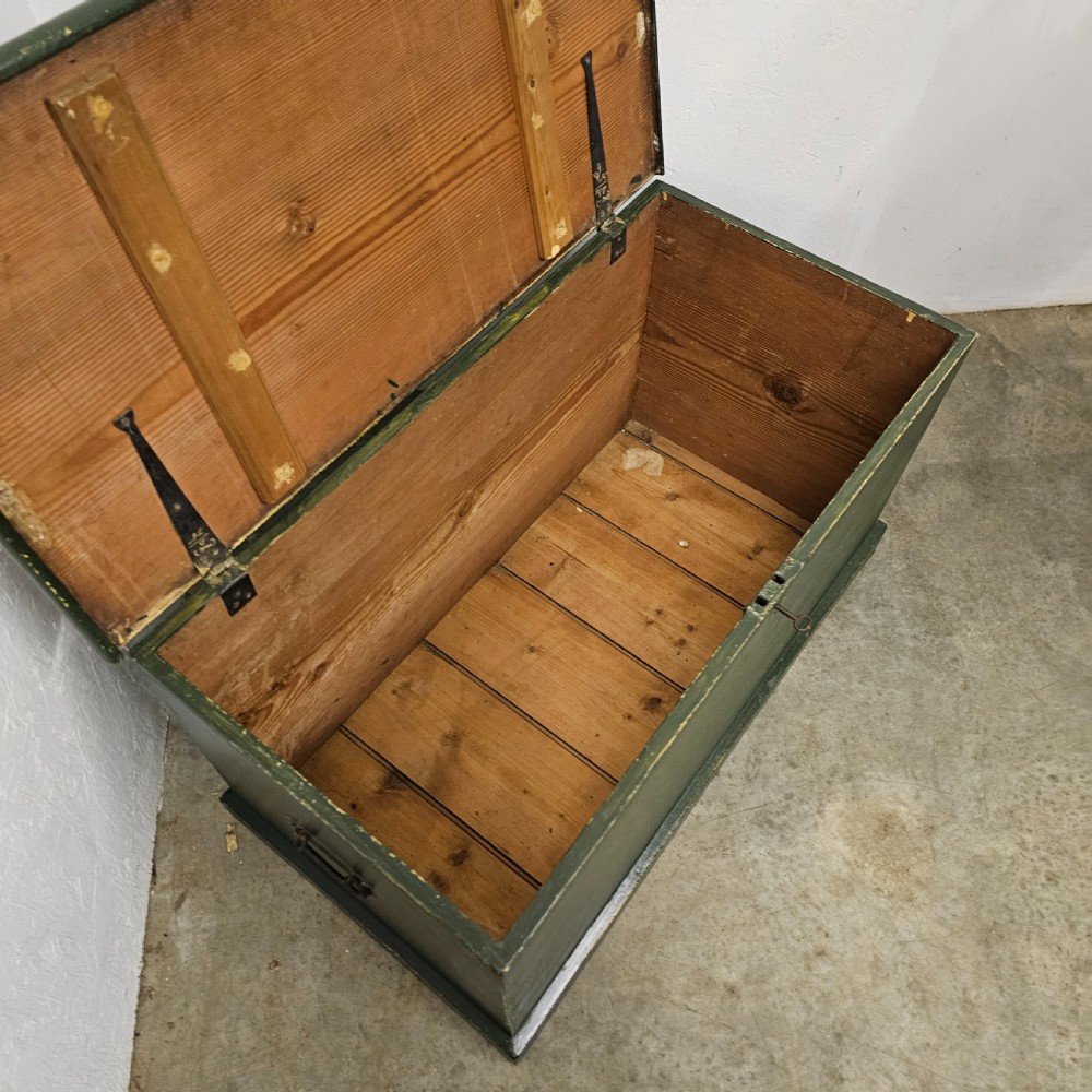 A rectangular green painted pine blanket box with side iron handles, a key in the lock, and a solid plinth base. View VII